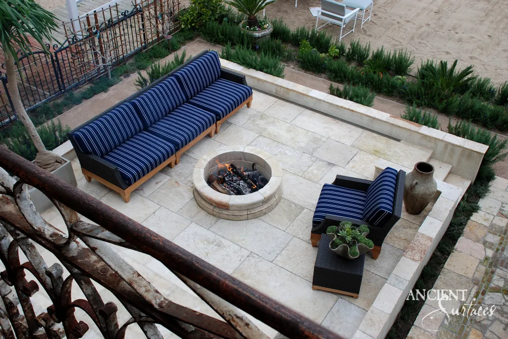 Reclaimed limestone paving laid around a round limestone fire pit on a waterfront terrace