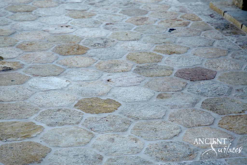 Reclaimed limestone paving laid as irregular hexagonal cobbles, showing natural gray and honey colored tones