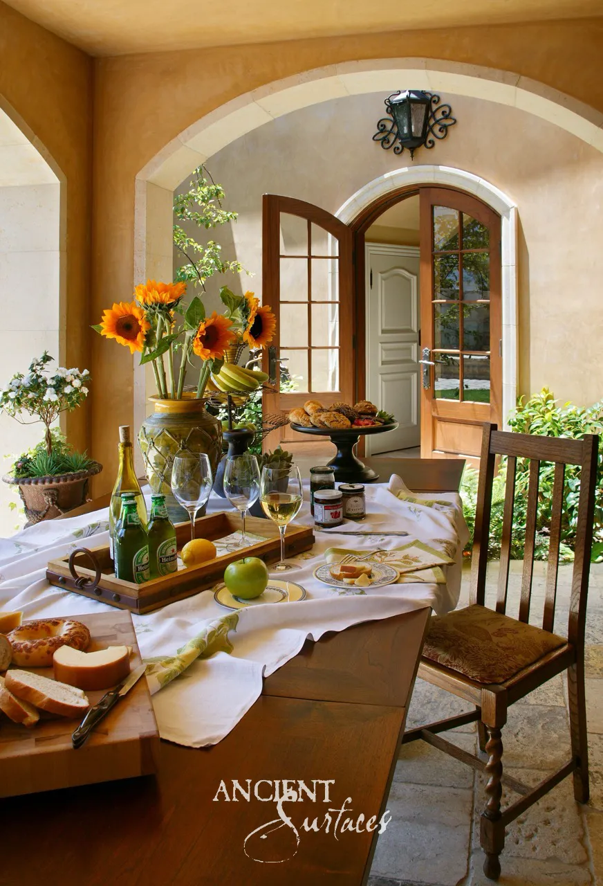 Limestone paved loggia with stone framed arches, set for lunch beside arched garden doors